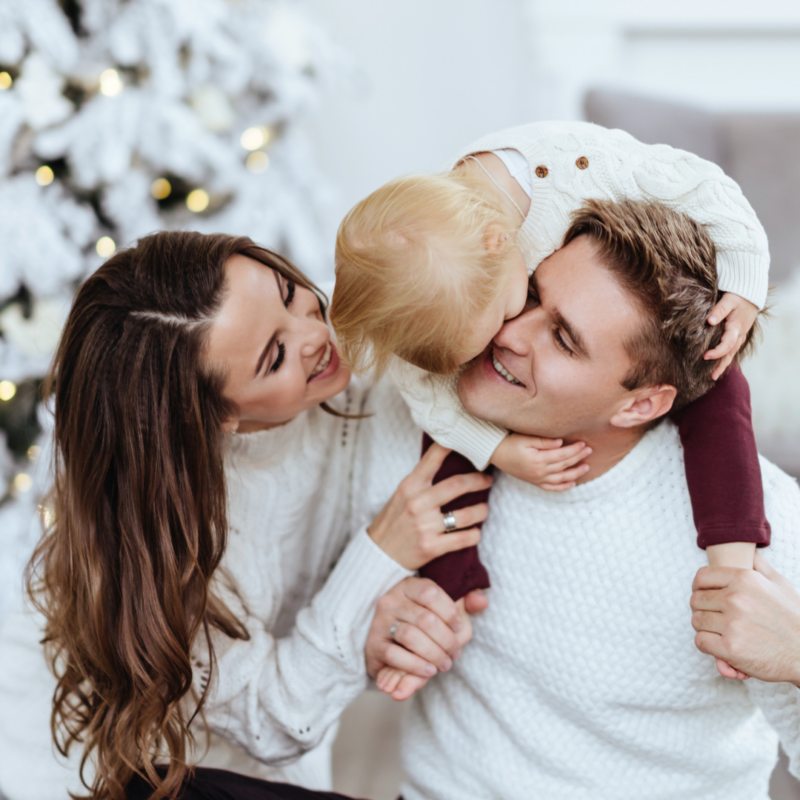 "Joyful parents holding their autistic child in a serene White Christmas wonderland, creating precious family memories."