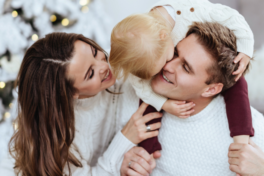 "Joyful parents holding their autistic child in a serene White Christmas wonderland, creating precious family memories."